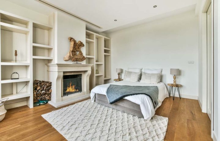 bedroom with a double soft bed and a carpet, hardwood floor and a fireplace